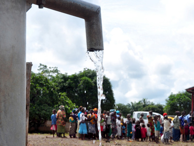 water pours out of a new well made by water for blue planet network in sierra leone