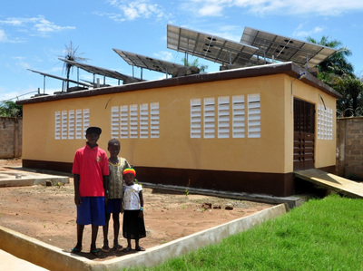 a family stands in front of their solar powered home in sierra leone